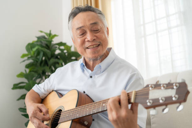 Senior Man Playing Guitar on Couch.
