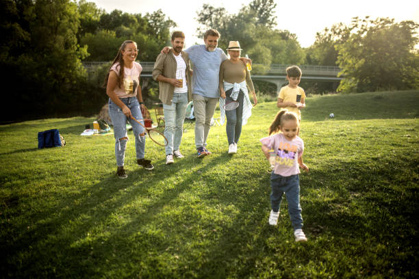 a multigenerational family is camping in a park by the river, capturing the family activity during an outdoor adventure