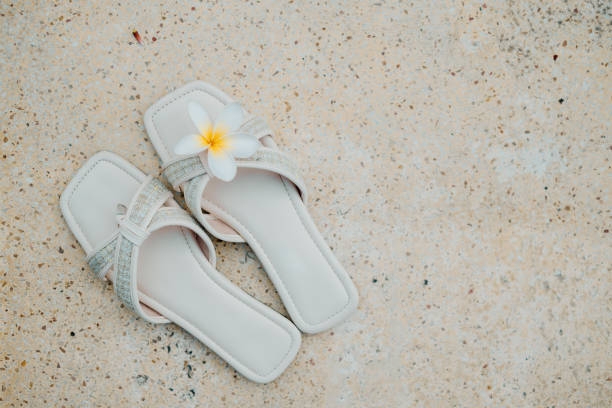 A pair of white flat sandals with Frangipani flower