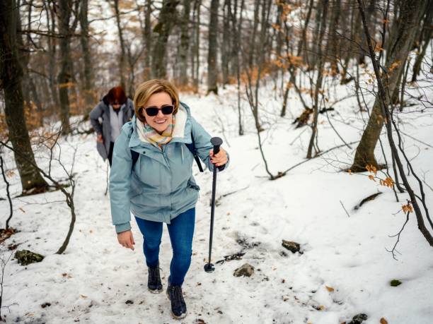 Hikers with trekking sticks climb steep mountain trail
