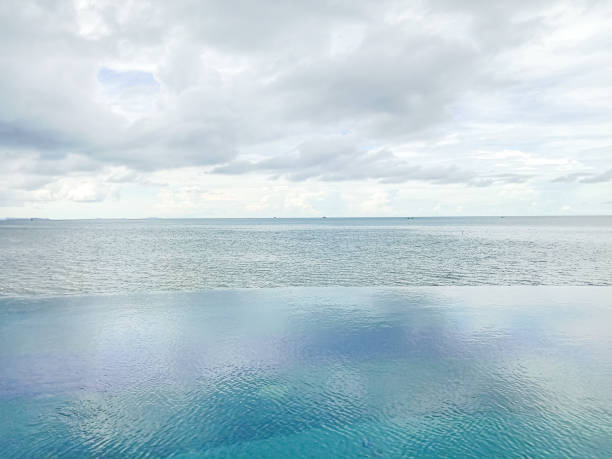 Infinity swimming pool with sea and ocean view background. White cloud, infinity pool, tropical sea. Summer vacation concept.