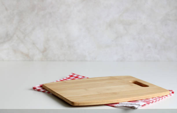 istock mockup of an empty cutting board and a checkered towel on the table. kitchen background. 2152686159