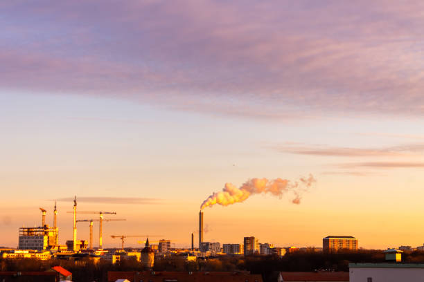 Sunset over Malmo, Sweden showcasing the contrast between natural beauty and industrial activity with smokestack emissions