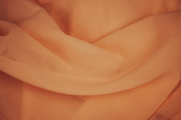 peach color colour background. Apricot colour pattern. Chiffon fabric. Fold satin background. Silk fabric background. Orange textile. Elegant decoration. Clothes texture with copy space.