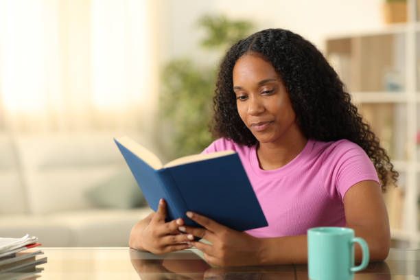 istock Black woman reading book at home 2152693831