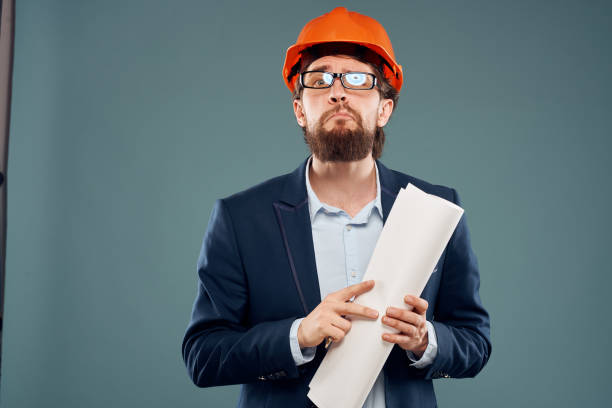 istock Male engineer professional orange hard hat safety construction blueprints in hands 2152694073