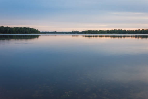 Sunrise over the forest lake. Reflection of the sky in the lake. Summer