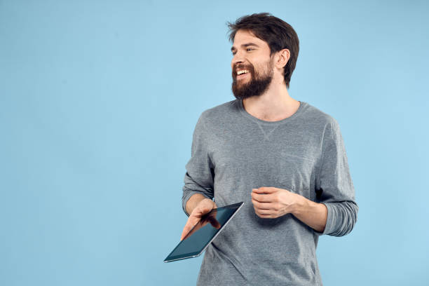 istock Man holding tablet in hands wireless technology internet lifestyle studio blue background emotions 2152696832