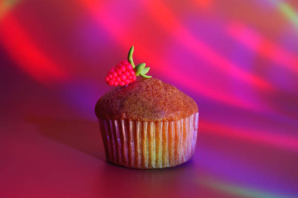Sweet muffin decorated with raspberries on a colored background.