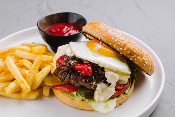 Appetizing gourmet burger with fried egg and fries