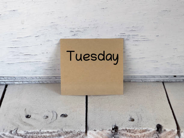 TUESDAY written on adhesive papers. On blurred styled background.