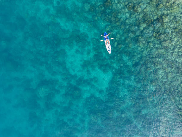 Aeriel panorama of young female person woman girl in red yellow kayak floating on clear blue ocean water Mallorca Majorca Balearic Islands, Mediterranean Sea Spain Europe