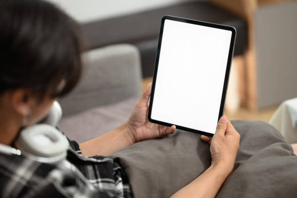 istock Close up view of young man holding digital tablet with blank desktop screen, lying on a sofa at home 2152699611