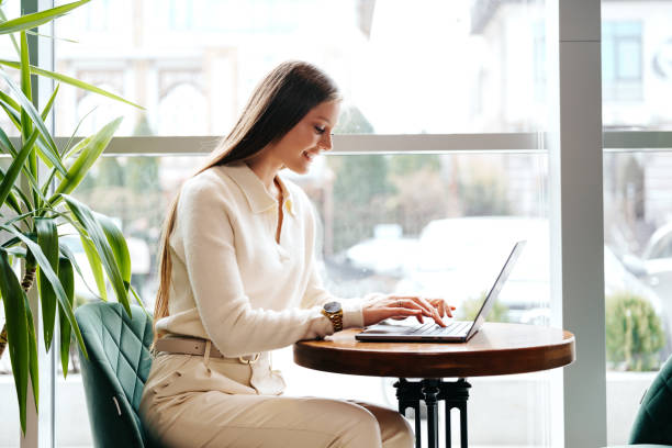 istock Smiling Woman Working on Laptop at a Cafe During Daytime 2152703663