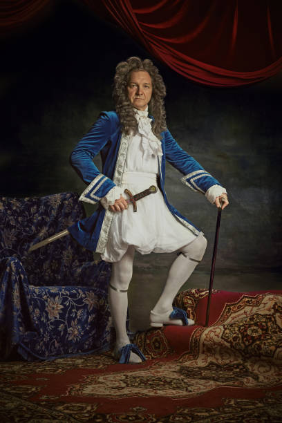 istock Confident, medieval person, senior man posing wearing old-fashioned clothes posing with sword against vintage studio background. 2152704692