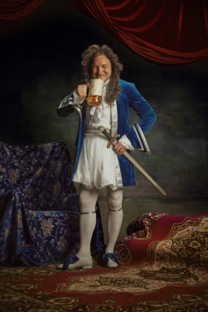 istock Happy elderly man, dresses as medieval person, king drinks cold refreshing alcohol drink, beer against vintage studio background. 2152704695