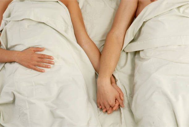 istock holding hand couple bed. 2152705435