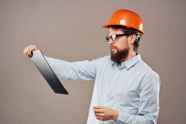 istock Man in orange hard hat professional safety manual documents work 2152707490