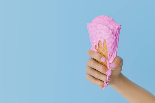 istock Hand Holding a Melting Pink Ice Cream Cone Against a Blue Background 2152708697