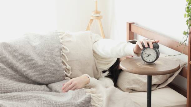 朝、目見本時計を消す女性 - 不眠症 ストックフォトと画像