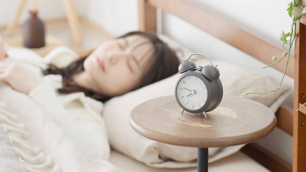 istock Woman setting an alarm clock and going to sleep 2152710274