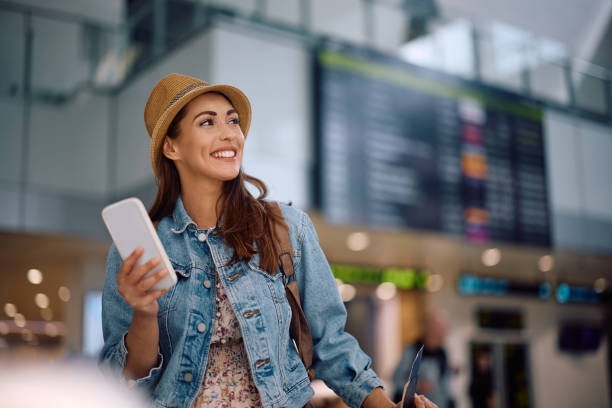 istock Happy traveler using cell phone while waiting for her flight at the airport. 2152712063