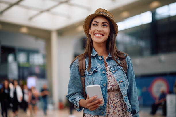 Young happy woman using mobile phone at departure terminal.