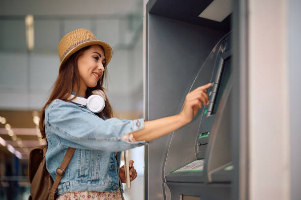 Young woman using ATM at the airport.