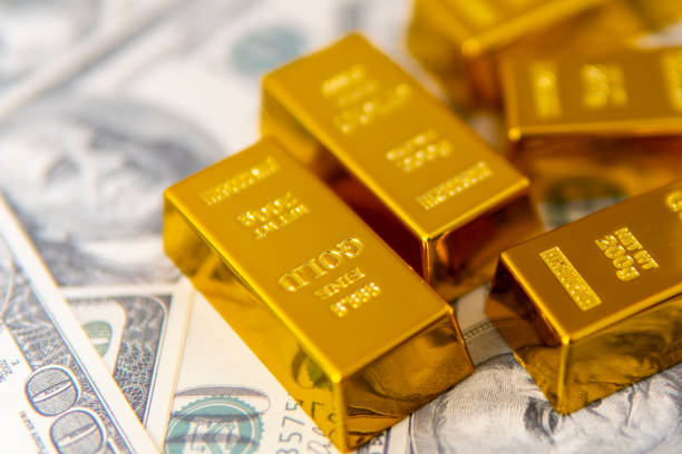 istock Gold bars on dollar bills: This image features shiny gold bars on a stack of $100 bills 2152713923