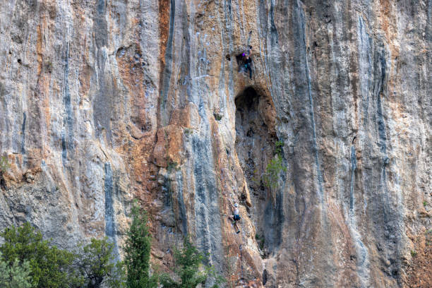 Athletic man climbs very high limestone rock with rope, lead climbing.. Sport climbing outdoor.