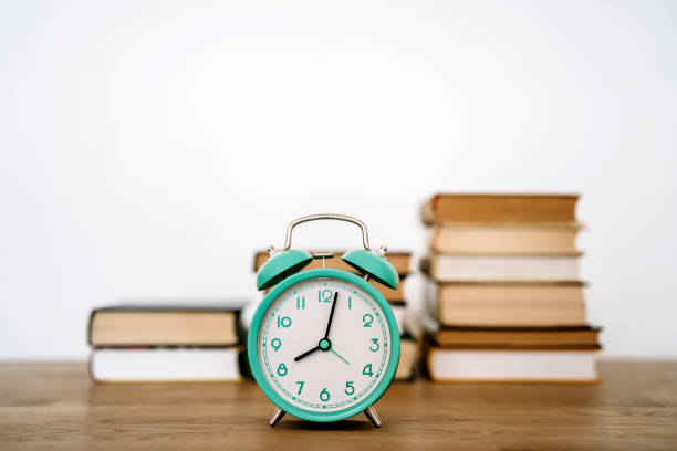 istock Books and alarm clock on a desk in a school or university classroom. Education, study concept background 2152716541