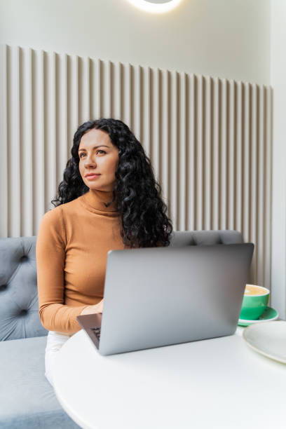 istock appy woman working in an office remotely from a cafe, using a laptop and drinking coffee. Distance learning, online learning and work 2152716735