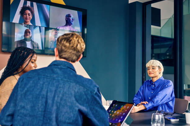 istock Team members in a modern office engaging with remote colleagues via a video conference call. Hybrid work environment and digital communication concept 2152719776