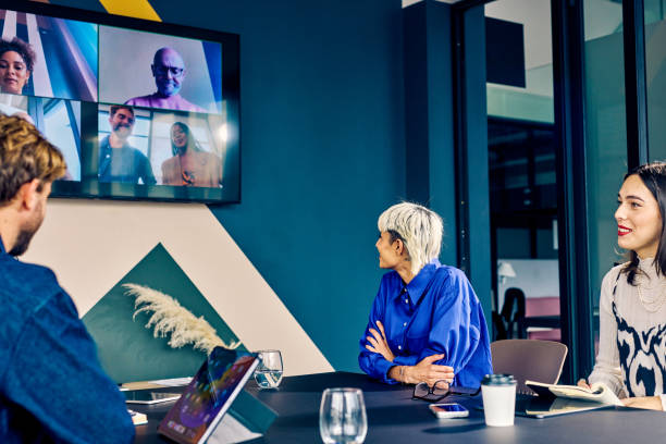 istock Team members in a modern office engaging with remote colleagues via a video conference call. Hybrid work environment and digital communication concept 2152719780