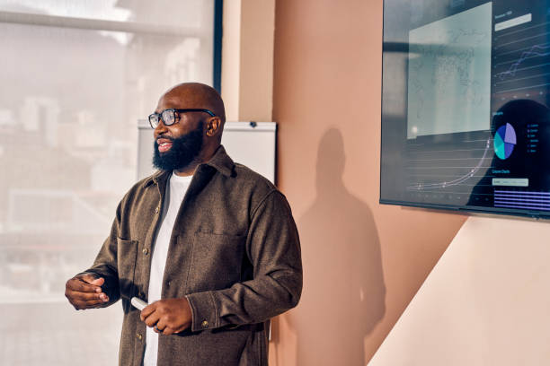 African American businessman presenting data analysis on a screen in a conference room. Professional presentation and strategic planning concept