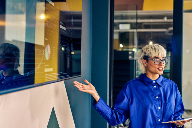 istock Professional Asian woman presenting data on a digital display in a corporate office. Effective communication and data visualization concept 2152719784