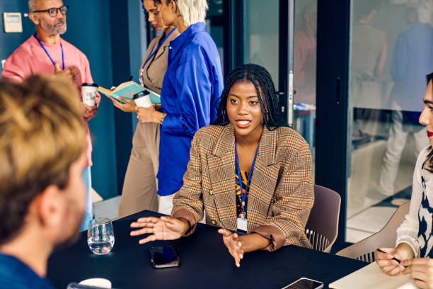 istock Gen Z co-worker discussing strategies with a colleague during a creative meeting. Multitasking and team collaboration in a diverse office environment concept. 2152719792