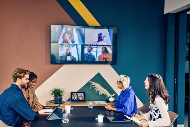 istock Team members in a modern office engaging with remote colleagues via a video conference call. Hybrid work environment and digital communication concept 2152719796