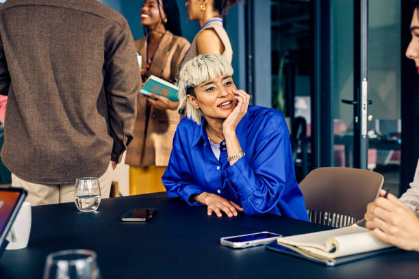 Gen Z co-worker discussing strategies with a colleague during a creative meeting. Multitasking and team collaboration in a diverse office environment concept.