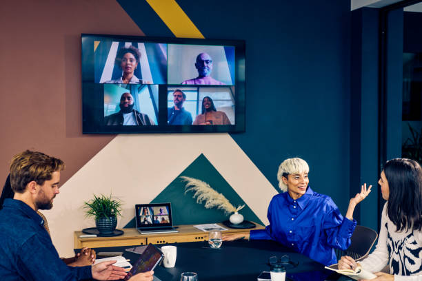 istock Team members in a modern office engaging with remote colleagues via a video conference call. Hybrid work environment and digital communication concept 2152719816