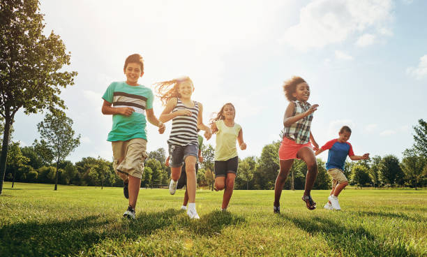 Making it a day of complete fun amigos felices, niños y correr con el campo de hierba en la naturaleza para divertirse, jugar o tomar el sol en el parque. diversidad o grupo de niños o jóvenes emocionados que disfrutan juntos de unas vacaciones soleadas al aire libre o un fin de seman