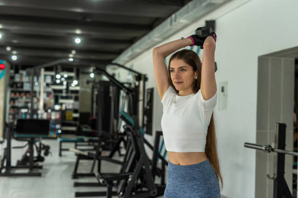 istock Caucasian female trainer doing biceps curl exercise with dumbbells in gym 2152723327