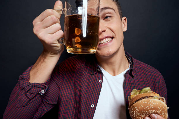 istock man with beer mug and hamburger in hands fun lifestyle studio dark isolated background 2152723977
