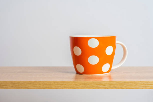 istock An big orange tea cup stands on a wooden surface. Light background with empty space on the theme of hot drinks. 2152730496