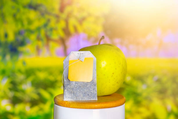 Tea bag with apple on a blurred background with sun and plantation.