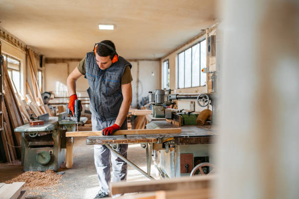 istock Young Male Carpenter Using An Electric Drill On The Wood In His Workshop 2152732253