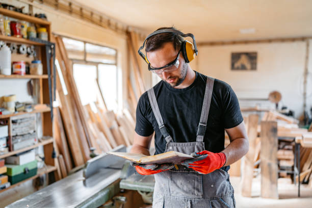 istock Young Male Carpenter Checking Measurements Written In The Notebook In His Workshop 2152732333