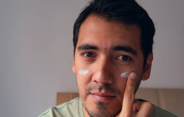 istock portrait of latin man applying moisturizer on his face 2152743219