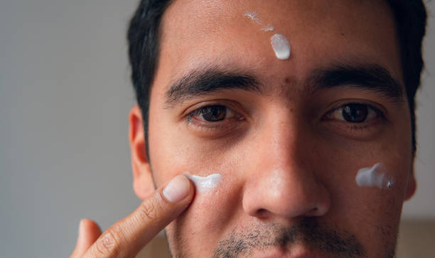 istock latin man applying moisturizer on his face 2152743318