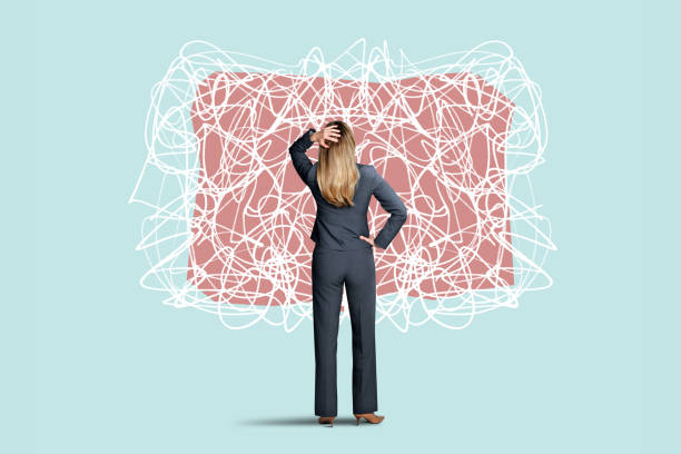 A rear view of a woman placing her hand on top of her head as she as she looks at some randomly drawn scribbled lines that convey the sense of confusion and chaos.